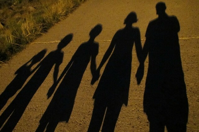 Shadow of family walking along a trail holding hands.